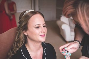 photo of bride on wedding day having make up applied